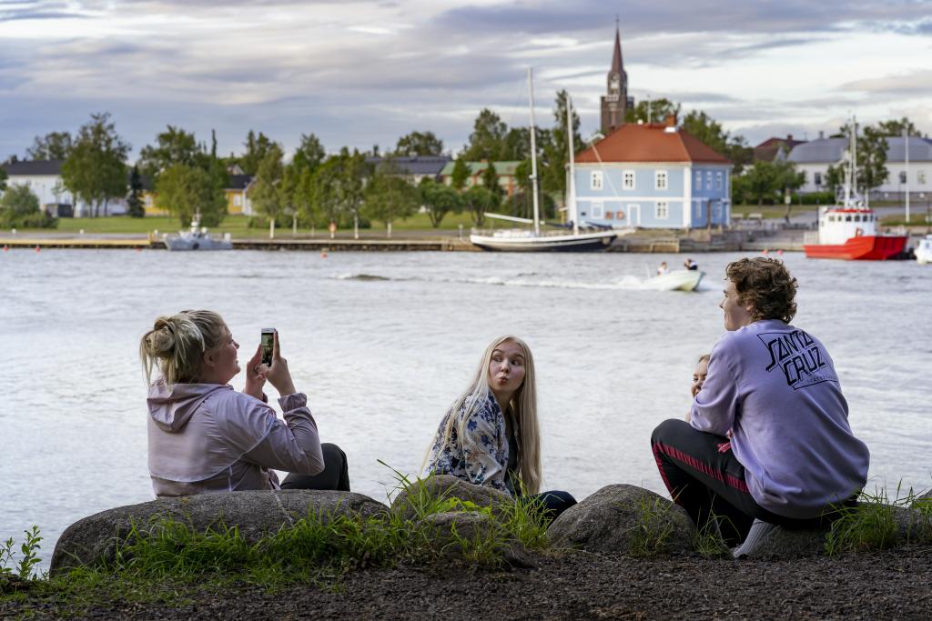 Nuoria rannassa, kaupunki ja meri taustalla.