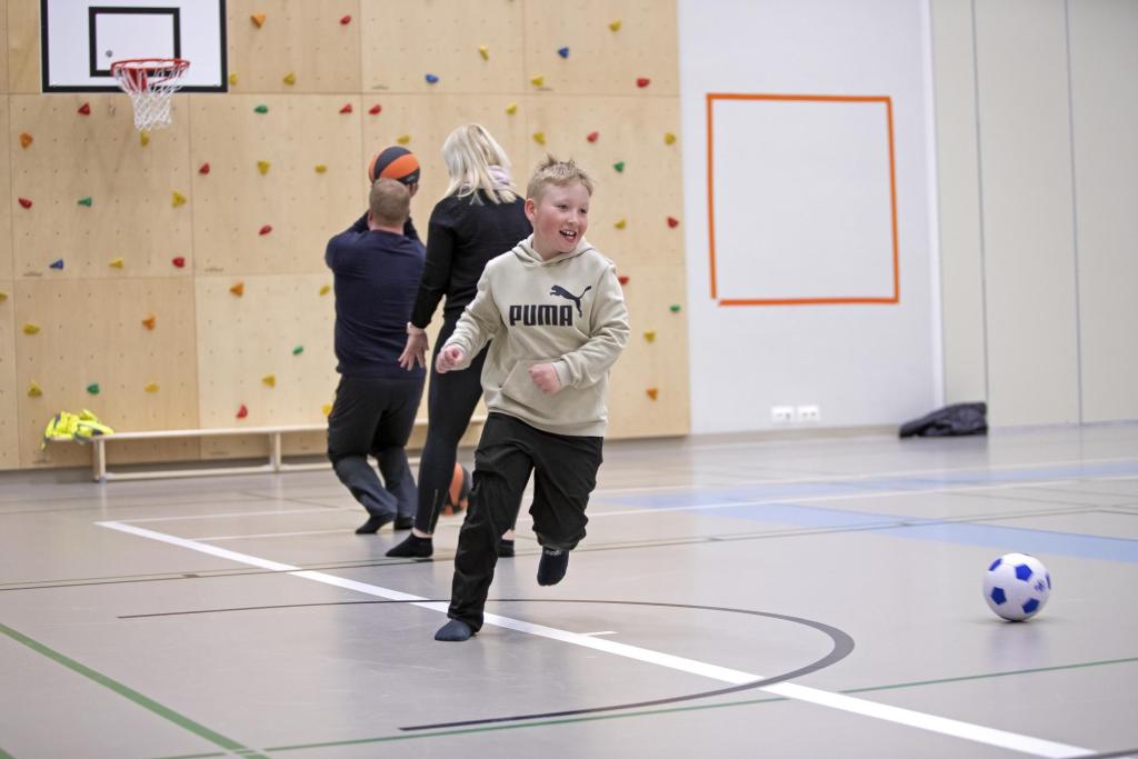 A mother and two children in gym, playing ball games.