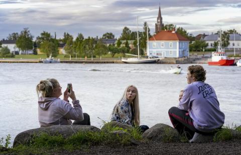 Nuoria rannassa, kaupunki ja meri taustalla.