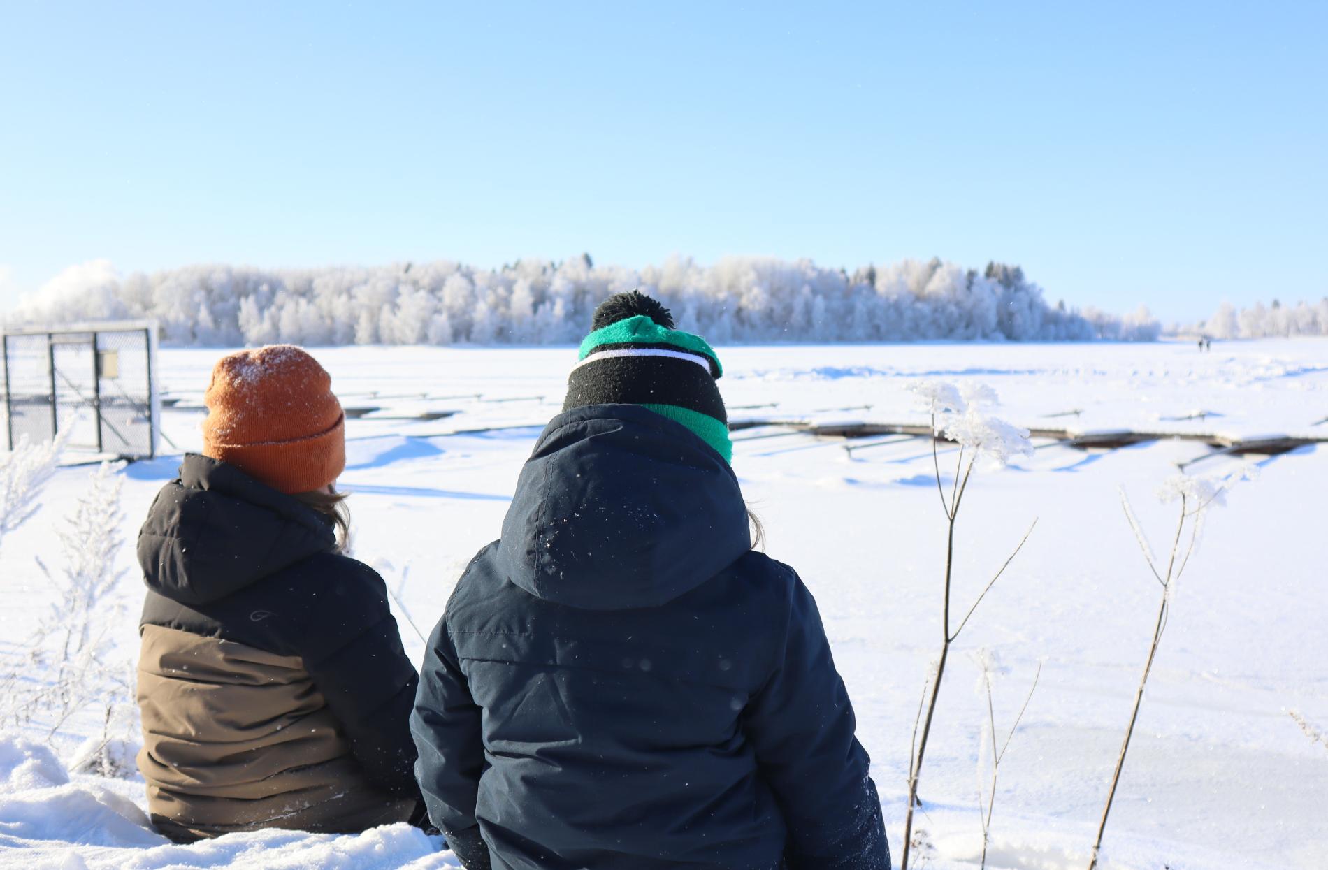 Barnen sitter vid Pikkulahti på vintern.