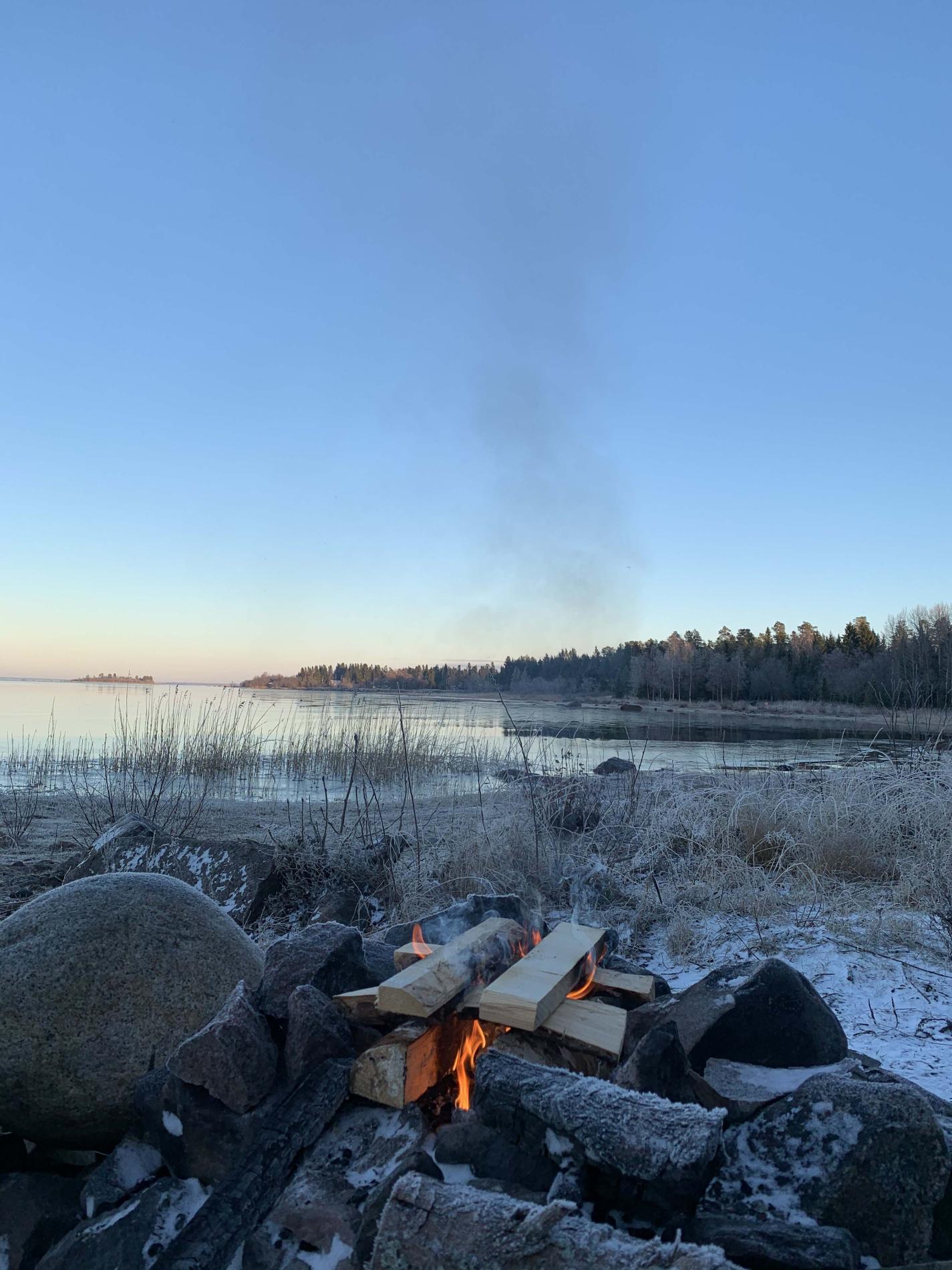 Nuotiolla meren rannassa alkutalvisena päivänä.